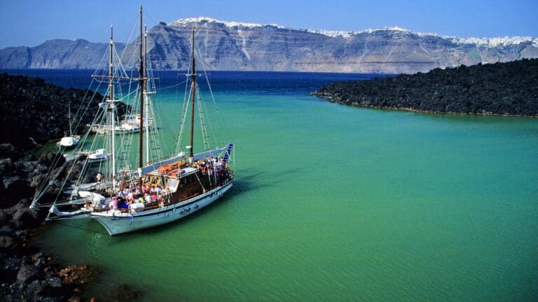 A boat sites in the teal waters off the coast of Santoini