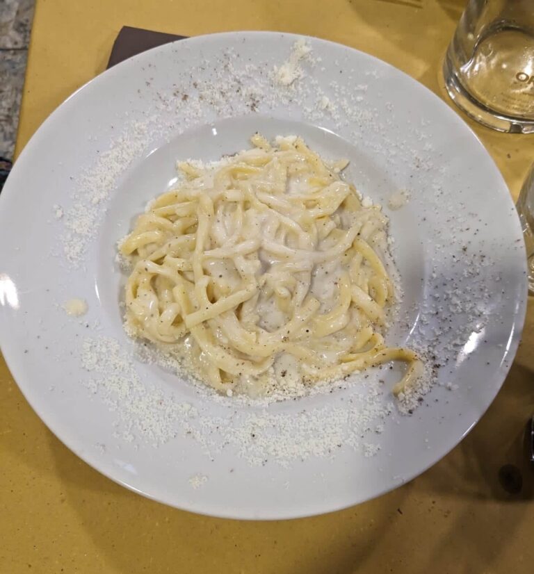 Plate of Cacio e Pepe pasta on a table with a brown paper table cloth in a restaurant in Rome