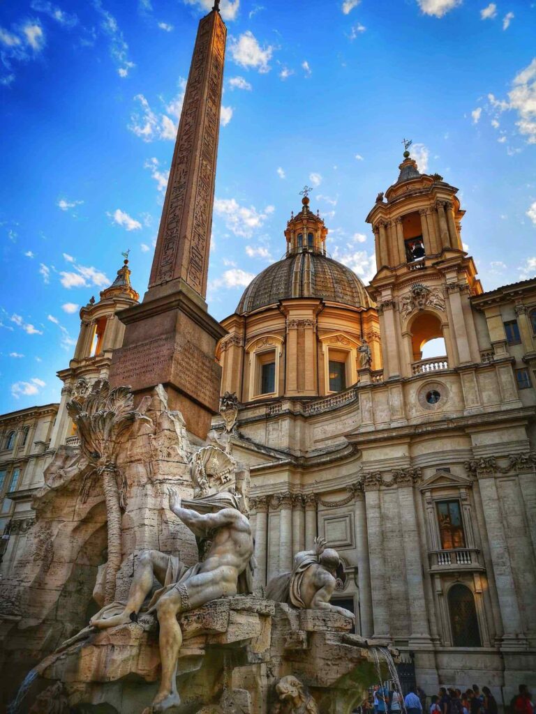 Dramatic photo of the fountain of the four rivers by bernini in piazza navona in rome showing the personification of the river nile with a veil over his eyes and face