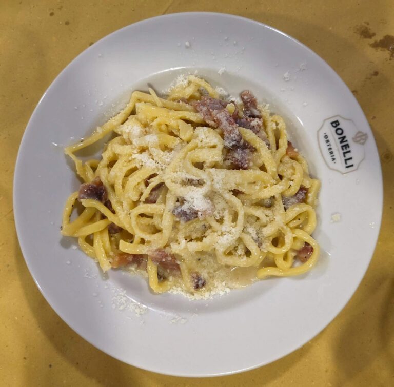 Plate of pasta alla Gricia on a white plate with the name of the restaurant printed on the plate Osteria Bonelli