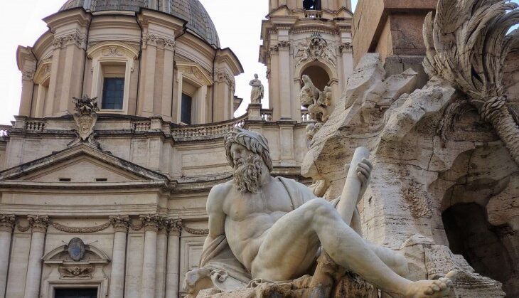 View of the fountain of the four river in piazza navona in rome showing a deatil of the statue of the personification of the river ganges with the church of saint agnes in agone in the background