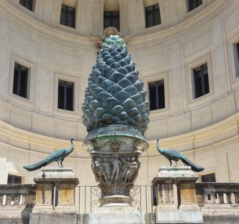 Photo of the Broze Pinecone flanked by two bronze peacocks in the Pinecone Courtyard