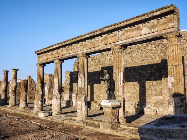 Colonnade of the Temple of Apollo in Pompeii showing a statue of a youth on a plinth outside