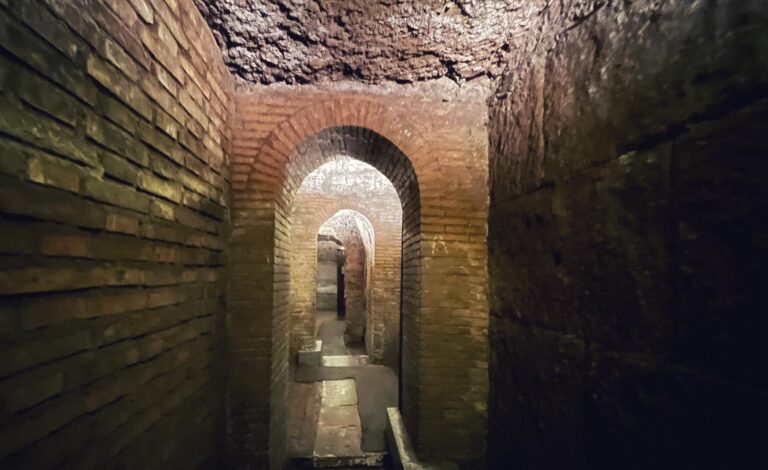 corridor in the underground excavations of the basilica of san clemente in rome leading to an underground river. the walls are constructed in brick and tuff