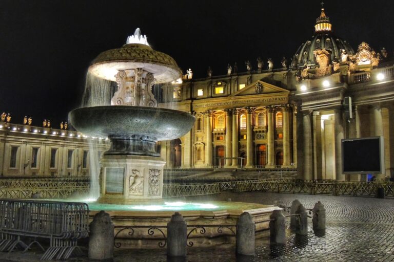 Fountain in St Peter's Square at night illuminated with St Peter's Basilica in the background, in Vatican city