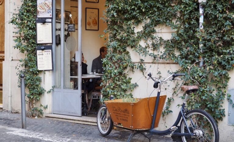 Facade of Zia Rosetta Sandwich shop in the Monti district of Rome with an ivy covered facade and an old fashioned delivery bicycle parked outside
