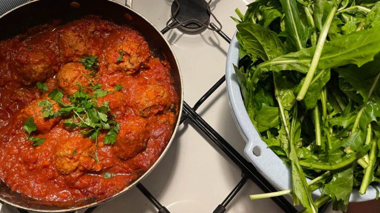 a pan of roman meatballs and cicoria ready to cook