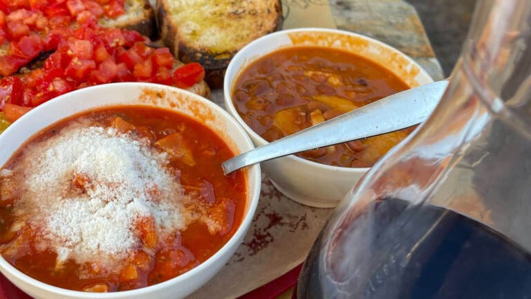 a bowl of roman tripe alongside beans and wine in ariccia