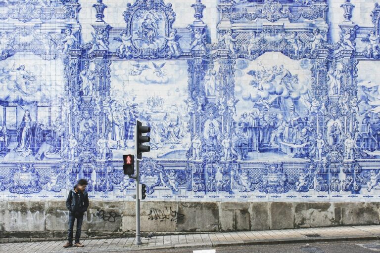 Man stands in front of Azulejos on the side of a church in Porto