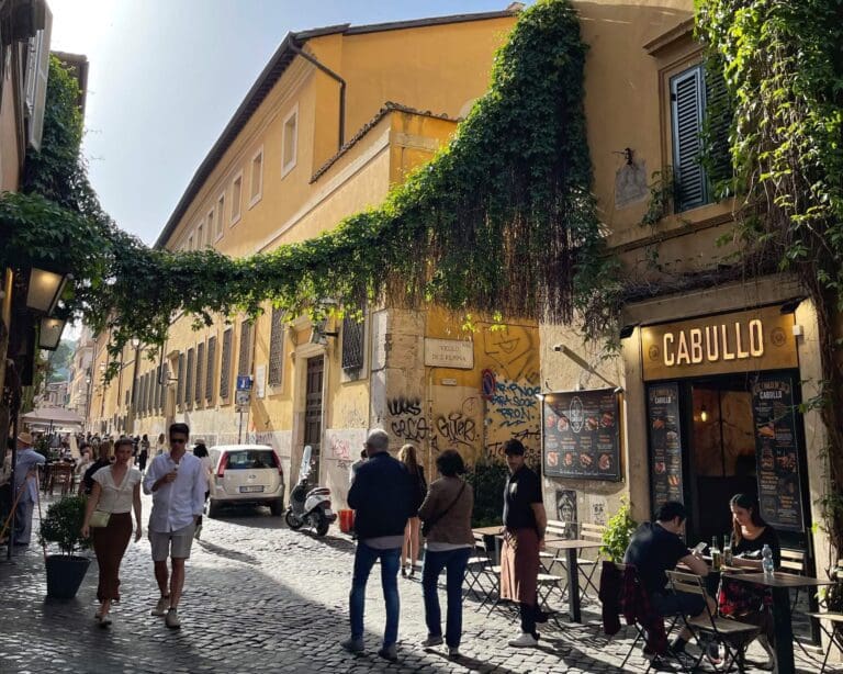 crowds walk down the streets of Trastever in Rome